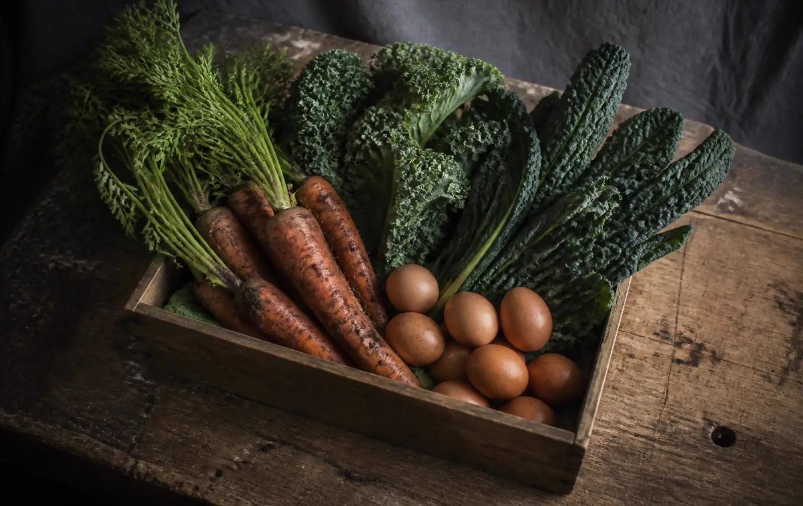 A crate of vegetables and eggs on a workbench